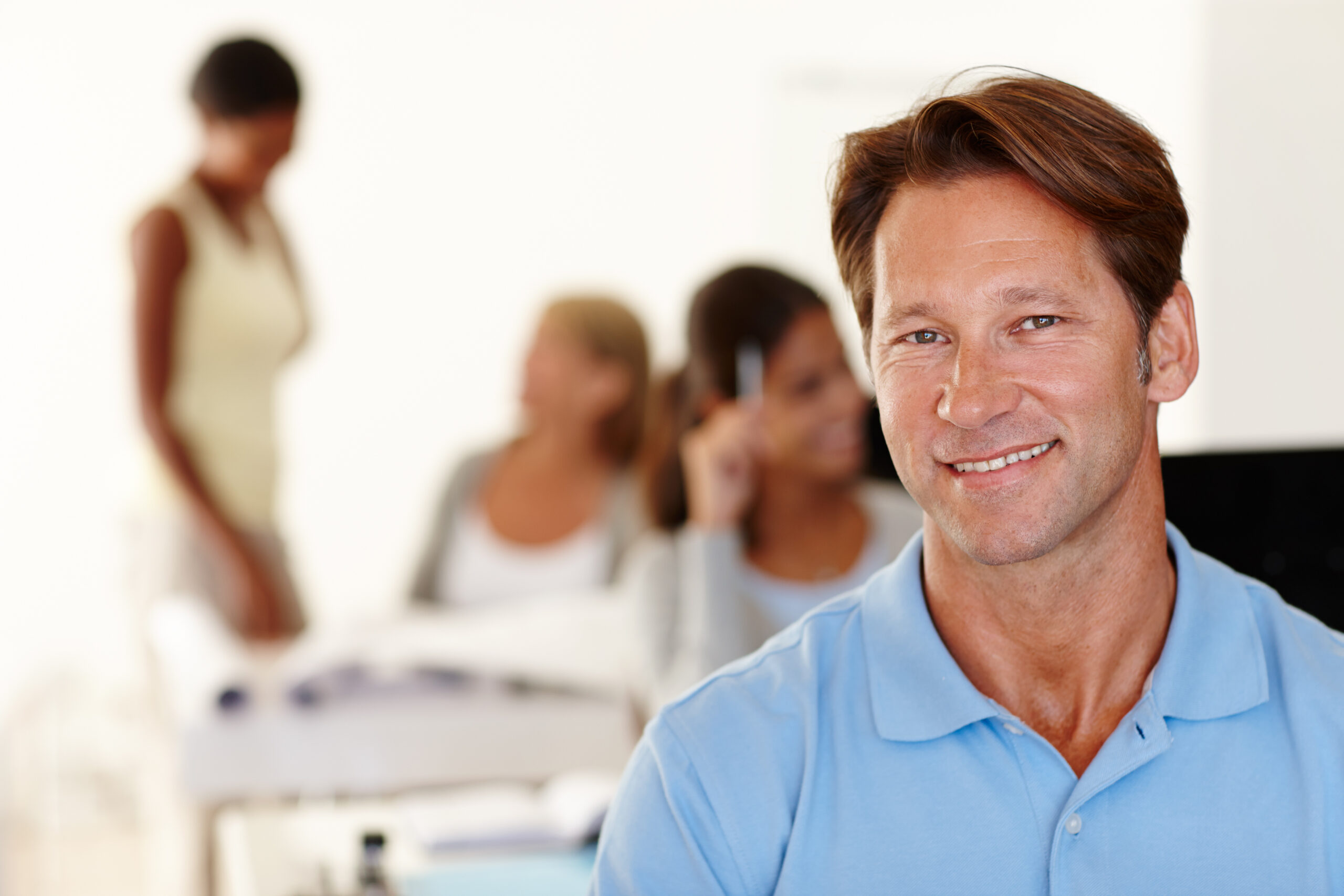 Smiling man with colleagues in a workspace.