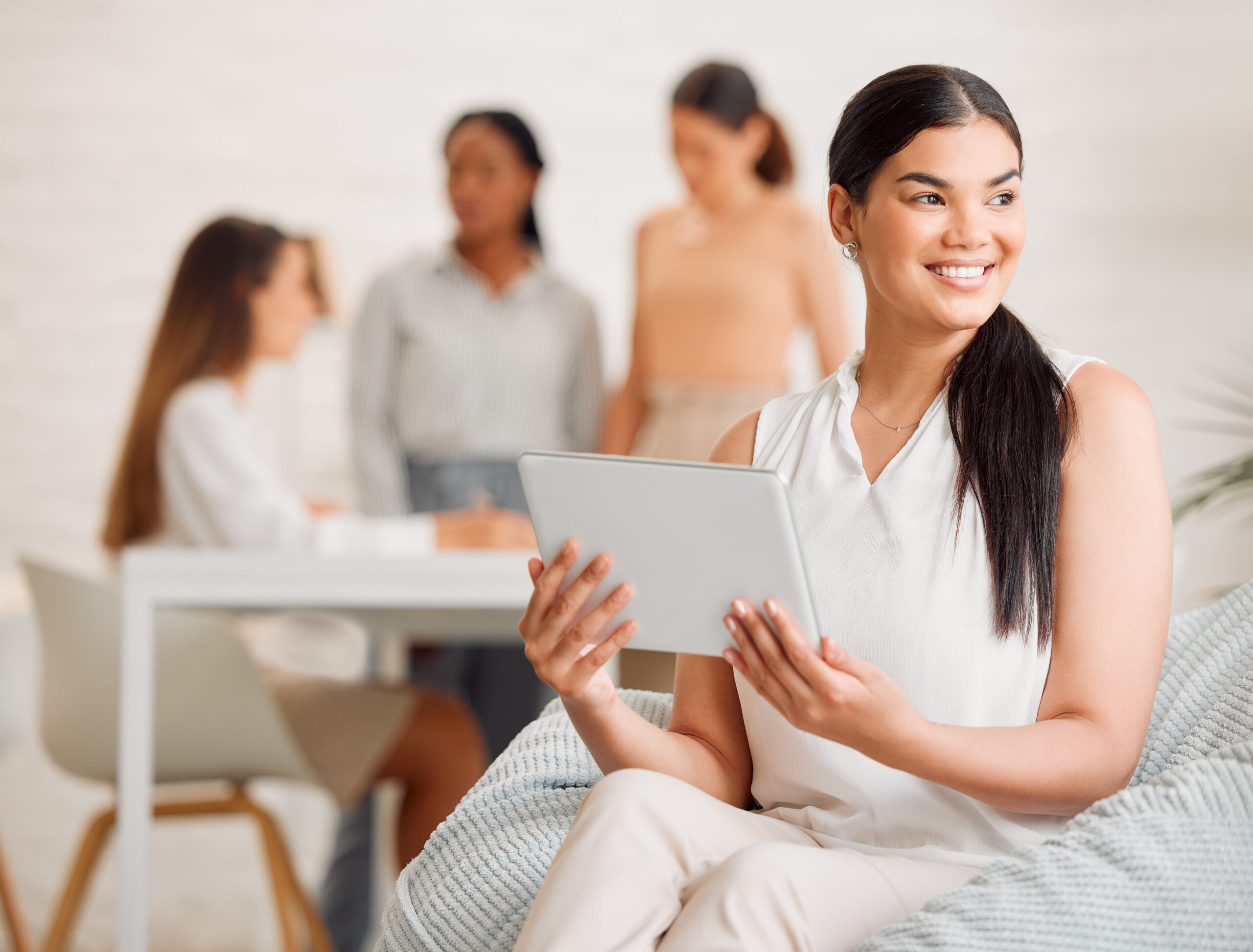 Smiling woman holding a tablet in a meeting.
