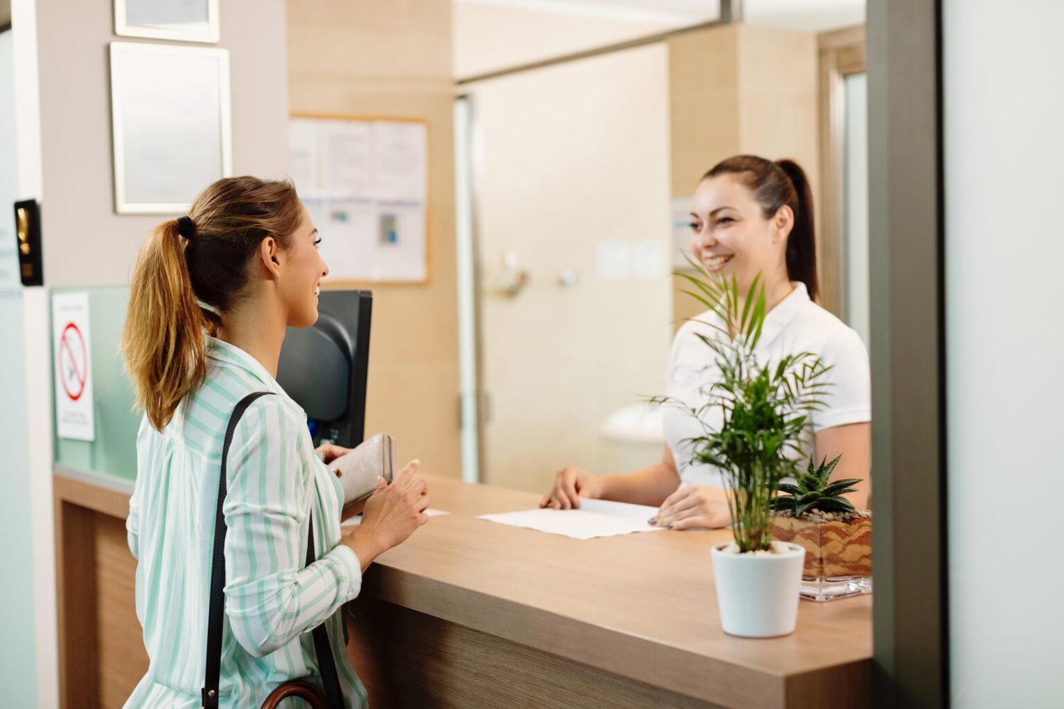 Two women interacting at a reception desk.