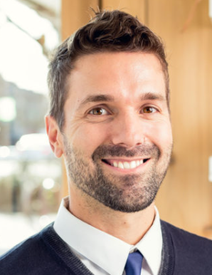 Smiling man with short hair in casual attire.